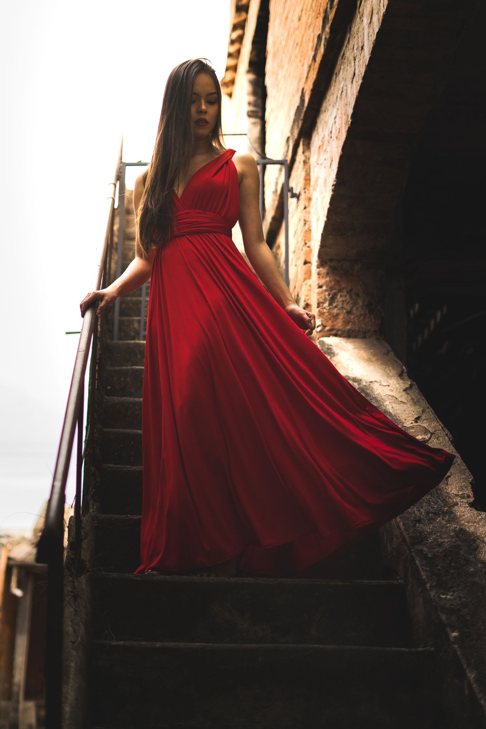 Woman in a flowing red dress on an old stone staircase